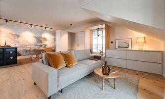 A modern living room with a comfortable sofa and decorative cushions. Light wood and natural elements create an inviting atmosphere.