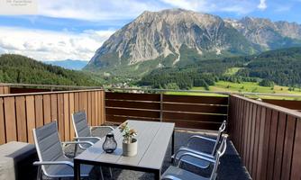 <p>A cozy terrace with a table and chairs. In the background, the majestic Grimming rises along with a green landscape.</p>