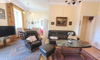 A cozy living room with an elegant couch and a coffee table. The room is brightly lit and has an inviting carpet.