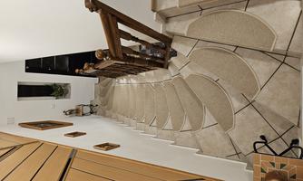 A curved staircase with beige carpet and a wooden railing. Pictures are hanging on the walls, and a plant is visible in the background.