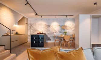 A modern living and dining room with a bright design. In the background, a large mountain landscape is depicted on the wall.