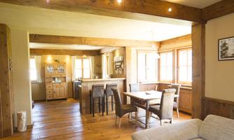 A cozy living space with wooden details and plenty of light. The kitchen and dining area are open plan and pleasantly furnished.