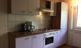 A modern kitchen with white cabinets and a wooden workspace. There is a stove, a refrigerator, and additional kitchen appliances.