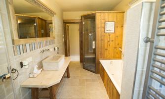 A modern bathroom with a shower and a bathtub. The walls are partially finished with tiles and wood.