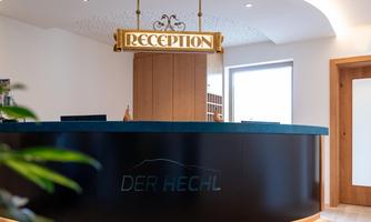 A modern reception desk with stylish LED lighting. In the background, a window and a wooden shelf are visible.