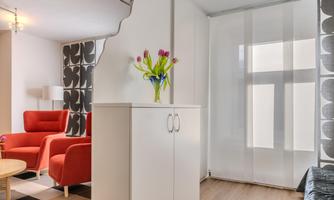 A cozy living room with red chairs and a white cabinet. A bouquet of tulips is on the table.