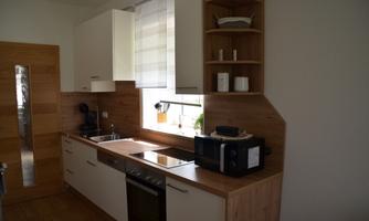 A modern kitchen with bright cabinets and a wooden surface. There are high-quality appliances and plenty of natural light.