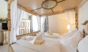 An elegant bedroom with a four-poster bed and cozy pillows. The bright curtains and stylish furniture create an inviting atmosphere.