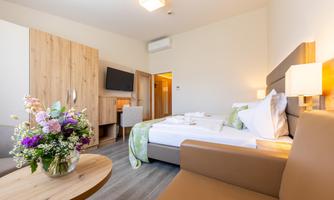 A bright and modern hotel room with a cozy bed and a seating area. A flower arrangement adds color to the room.