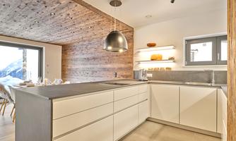 A modern kitchen with bright cabinets and a large kitchen island. The room has wooden details and large windows overlooking the outside.
