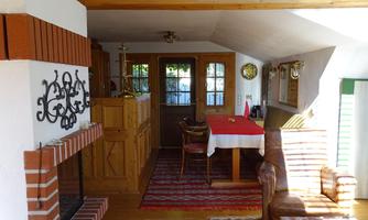 A cozy living space with an open fireplace and wooden decor. The table is beautifully set, and large windows let in plenty of light.