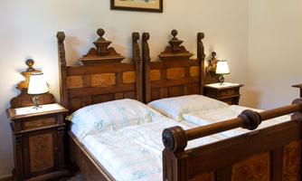 A cozy bedroom with a large wooden double bed and two nightstands. Soft lighting creates a relaxed atmosphere.