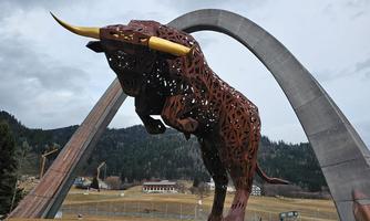 An impressive sculpture of a bull-like animal made of metal. In the background, an arched building is visible.