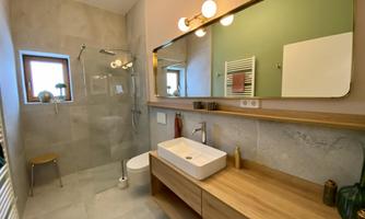 A modern bathroom with a shower and an elegant wooden shelf. The wall mirrors reflect the soft light and create a pleasant atmosphere.