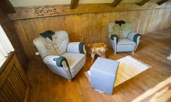 A cozy room with two stylish armchairs and a small table. The furniture has a rustic design and the floor is made of wood.