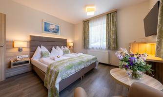 A modern hotel room with a double bed and stylish decor.  
Fresh flowers and natural lighting create an inviting atmosphere.
