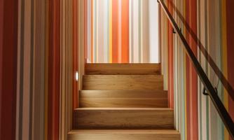 A wooden staircase with colorful, striped walls. The ascent feels inviting and modern.