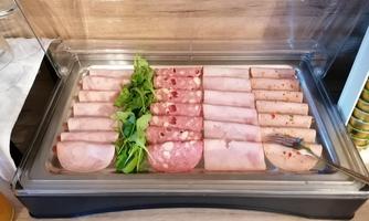 A selection of cold cuts and sausages on a tray. Fresh salad complements the presentation.