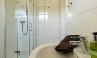 A modern bathroom with a shower and a sink. Towels and soap are neatly placed.