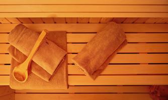 A sauna with wooden shelves and brown towels. A wooden spoon is ready for use.