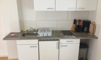 A modern kitchen with a sink, a refrigerator, and kitchen appliances. The room is bright and tidy.