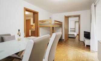 A bright and modern apartment with a dining area and bunk beds. The rooms are tidy and inviting.