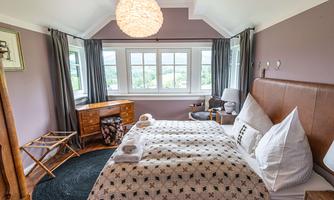 A cozy bedroom with a large bed and modern furniture. 

Large windows provide plenty of daylight and a pleasant view outside.