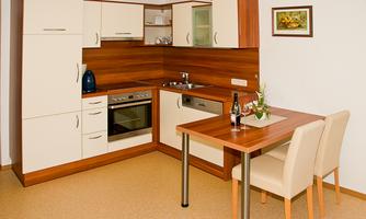 A modern kitchen with light cabinets and wooden accents. A table with two chairs is ready to enjoy meals.