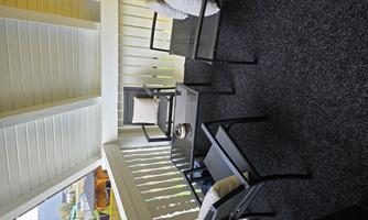 A cozy balcony with black furniture and soft cushions. The floor is covered with carpet and the walls are painted yellow.