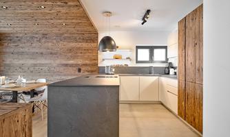 Modern kitchen with wood and stone elements. An elegant dining table complements the cozy atmosphere.