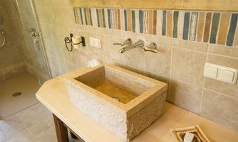 A modern bathroom with an elegant wall-mounted sink and stylish fixtures. The walls are adorned with neutral tiles and decorative accents.