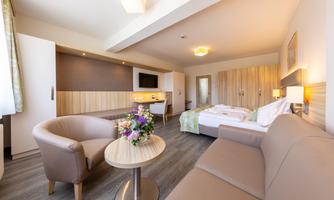 A modern room with a cozy seating area and a large bed. Bright colors and an inviting atmosphere create a relaxing environment.