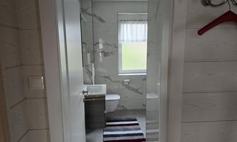 A modern bathroom with a white toilet and a washbasin. The floor is decorated with a striped rug.