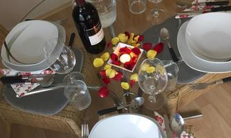 A beautifully set table with white plates, glasses, and cutlery. In the center, there is a decorative candle and table decoration in warm colors.