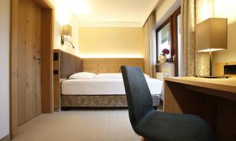A modern hotel room with a single bed and a desk. The room is brightly and cheerfully designed.