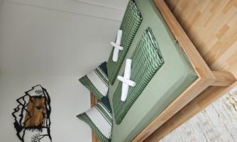 A cozy bed with green and white striped cushions and freshly folded towels. The wall is adorned with a decorative mountain landscape.