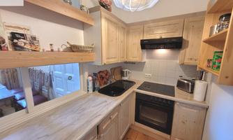 A bright kitchen with wooden shelves and modern appliances. The walls are painted in neutral colors and the countertop is made of light materials.