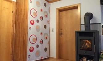 A cozy room with wooden flooring and modern heating. A decorative curtain with colorful circles hangs on the wall.
