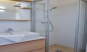 A modern bathroom with a shower and a sink. The walls are bright and the floor is tiled.