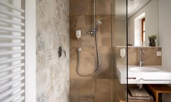 A modern bathroom with a stylish shower and elegant tiles. The sink area is bright and inviting.