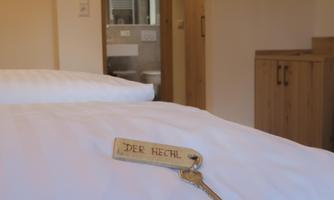 A sleeping area with two beds and a key on the bedspread. In the background, a bathroom area can be seen.