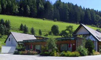 A modern building in a rural setting with a beautiful garden. In the background, green meadows and trees can be seen.
