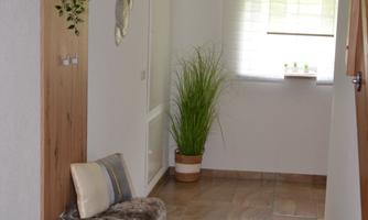 A bright hallway with a cozy bench and plants. The large windows provide plenty of daylight.