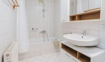 A modern bathroom with a bathtub and sink. The walls are tiled with white tiles and there are bright, decorative shelves.