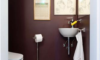 A modern bathroom with dark wall colors and elegant pictures. The floor is decorated with an attractive patterned tile.