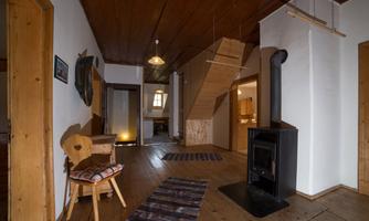 An inviting hallway with a wood stove and wooden furniture. The floor is decorated with a colorful carpet and the walls are in neutral colors.