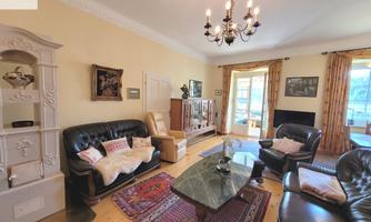 A cozy living room with leather furniture and a beautiful rug. Large windows provide plenty of light and an inviting atmosphere.