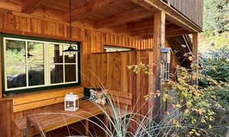 A cozy wooden terrace with a table and chairs. Surrounded by green plants and a peaceful atmosphere.