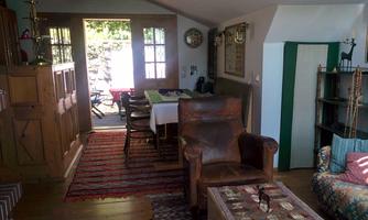 A cozy room with wood details and a dining table. The large windows let in plenty of light and lead to a terrace.