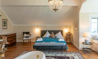 A stylish bedroom with a comfortable bed and a freestanding bathtub. The decor is modern and invites relaxation.